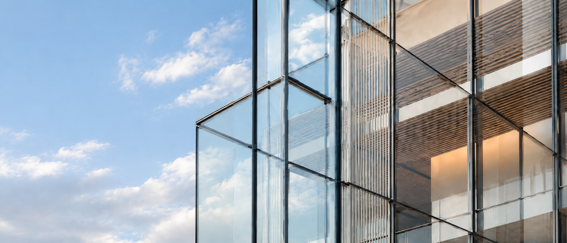 Modern glass-and-steel commercial building facade reflecting a blue sky